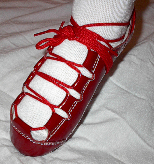 A person wearing a pair of Celtic Choice Patent Leather Red shoes.