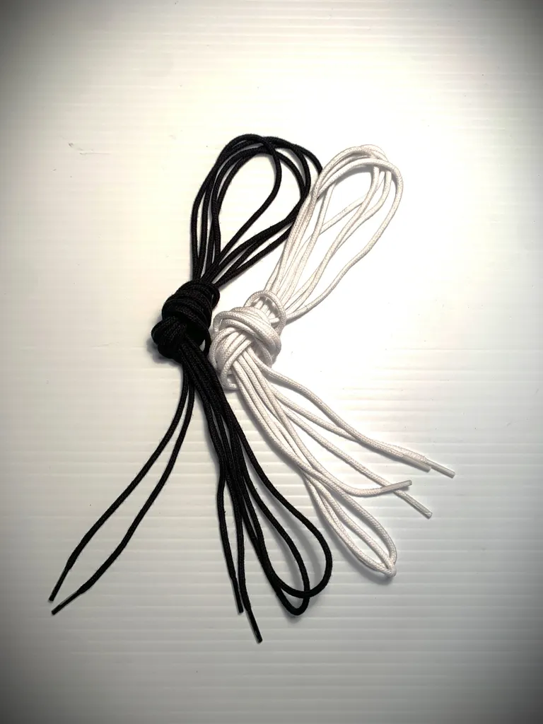 A pair of Soft Shoe Laces in black and white on a white surface.