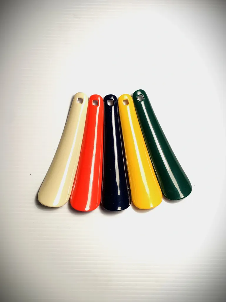 Five different colored shoe horns on a white surface.