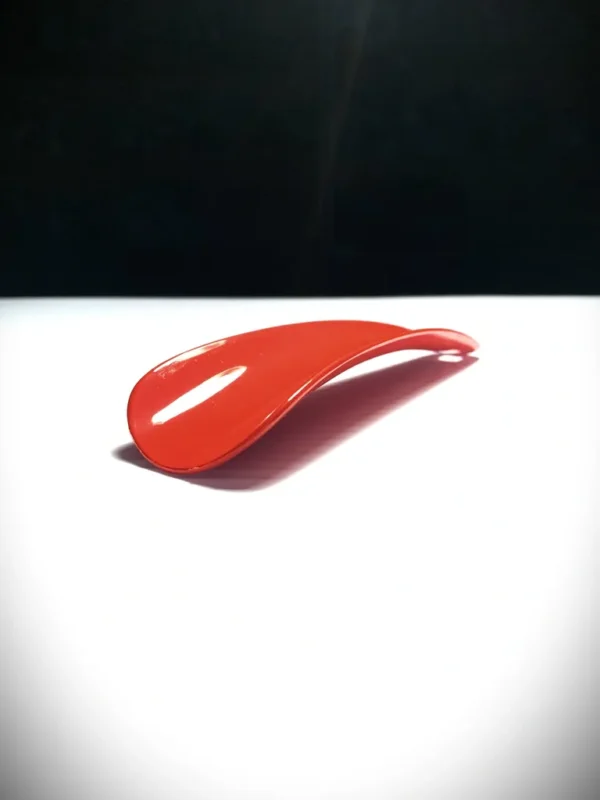 A red Shoe Horn sitting on a white surface.