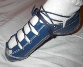 A person wearing a pair of Celtic Choice Patent Leather Blue shoes on a bed.