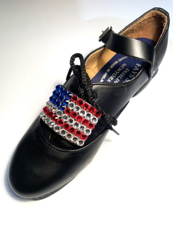 A pair of black shoes with Flag of the United States buckles on them.