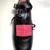 A black shoe with Pink Buckles on it.