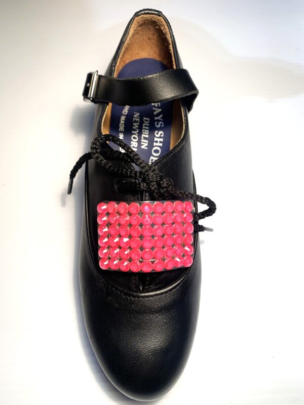 A black shoe with Pink Buckles on it.