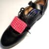 A pair of black shoes with Pink Buckles on them.