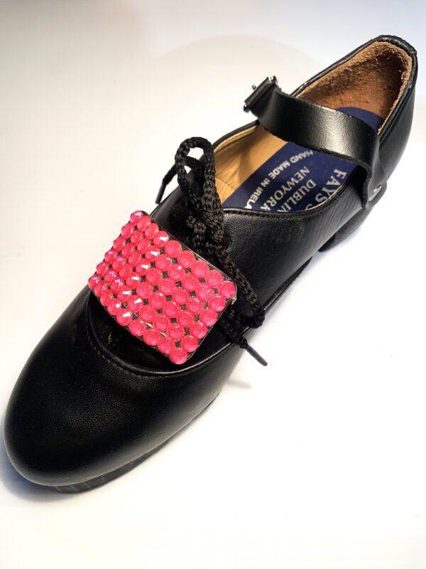 A pair of black shoes with Pink Buckles on them.