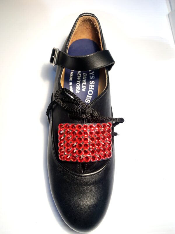 A pair of black shoes with Red Buckles.