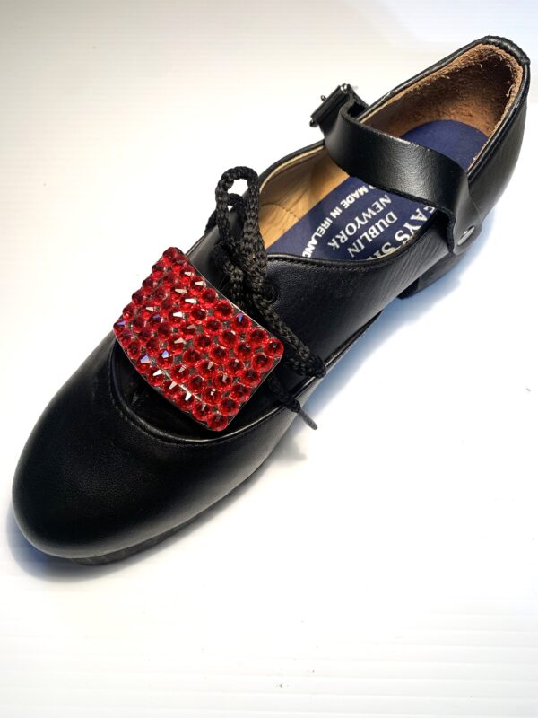 A pair of black shoes with Red Buckles.